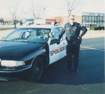 Officer Brian Coash standing by squad car