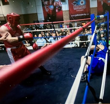 Brian Coash in a boxing ring standing above his opponent